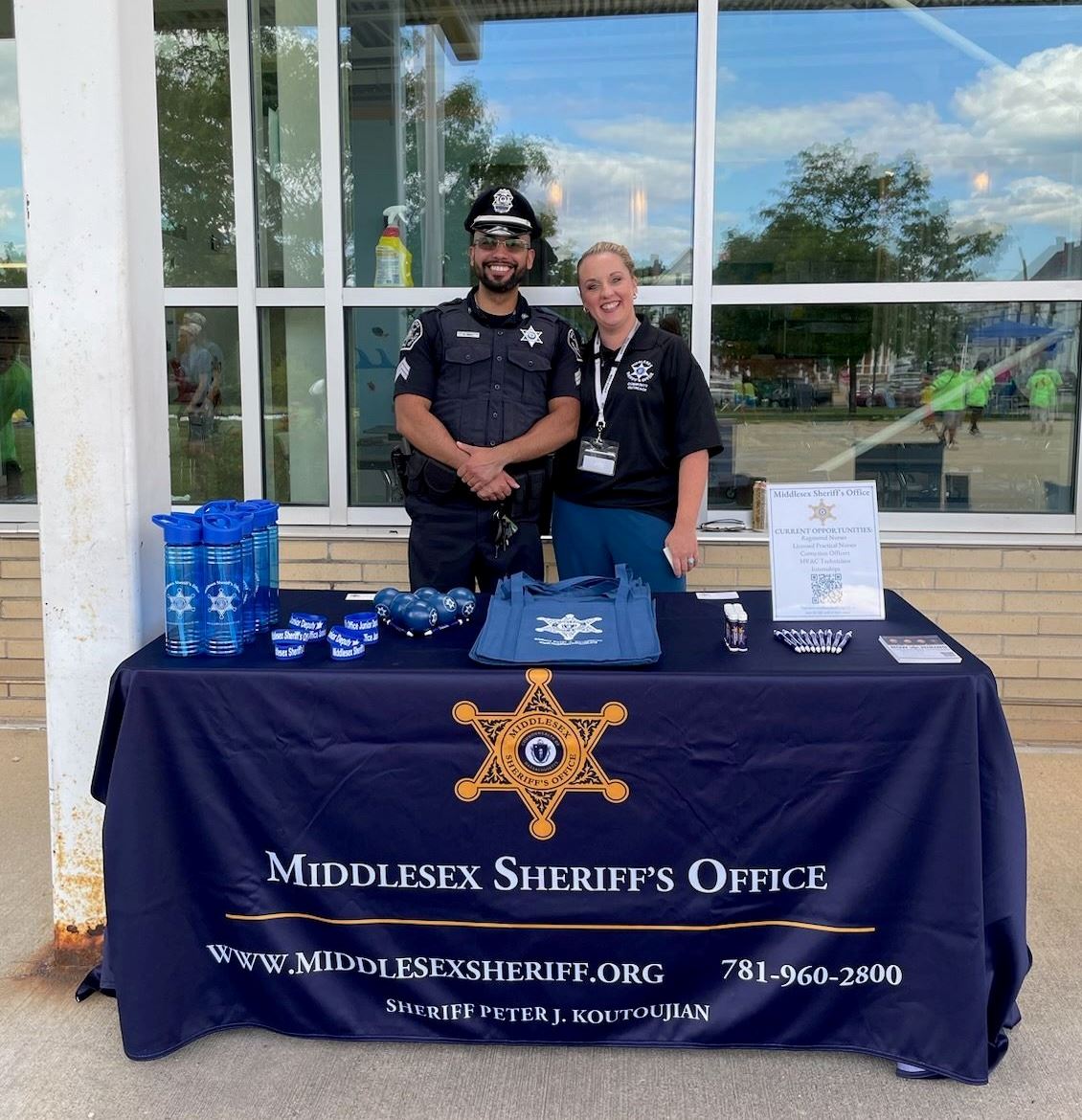Two employees standing behind a table at National Night Out 