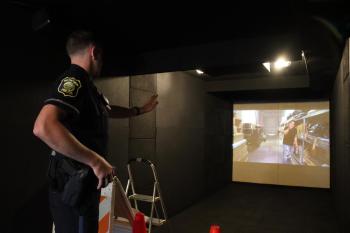A Medford police officer with a screen in front of him participates in an interactive, scenario-based training inside the Middlesex Sheriff's Office Mobile Training Center.