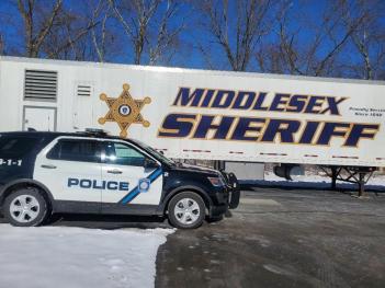 A Littleton Police Department SUV is parked beside the Middlesex Sheriff's Office Mobile Training Center.